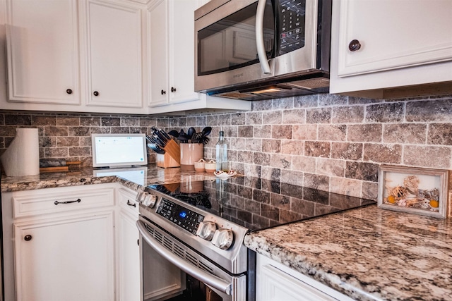 kitchen with backsplash, stainless steel appliances, white cabinets, and stone countertops