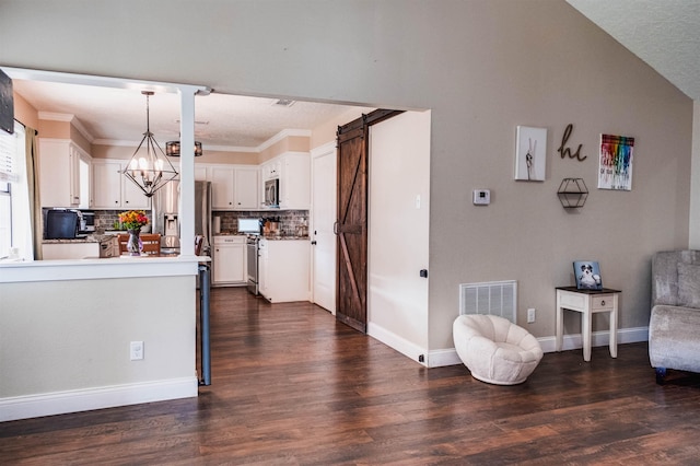 kitchen featuring stainless steel appliances, white cabinetry, a barn door, and pendant lighting