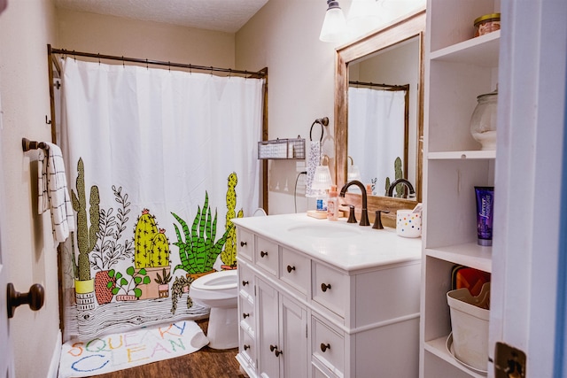 bathroom featuring curtained shower, hardwood / wood-style floors, vanity, toilet, and a textured ceiling