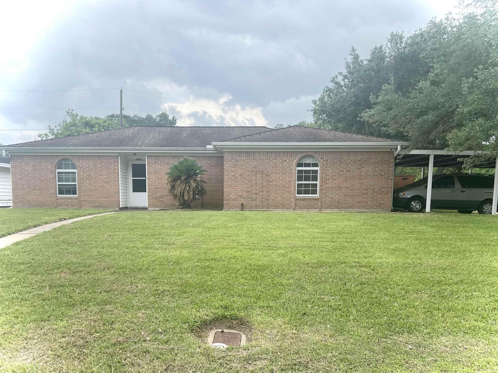 view of front of house featuring brick siding, a front yard, and a carport