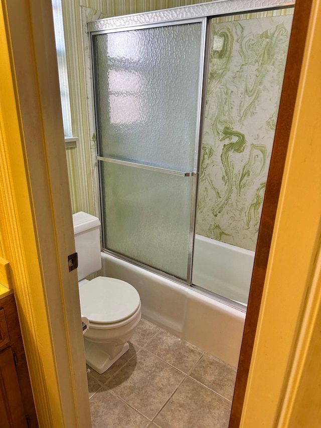 bathroom featuring shower / bath combination with glass door, tile patterned flooring, and toilet