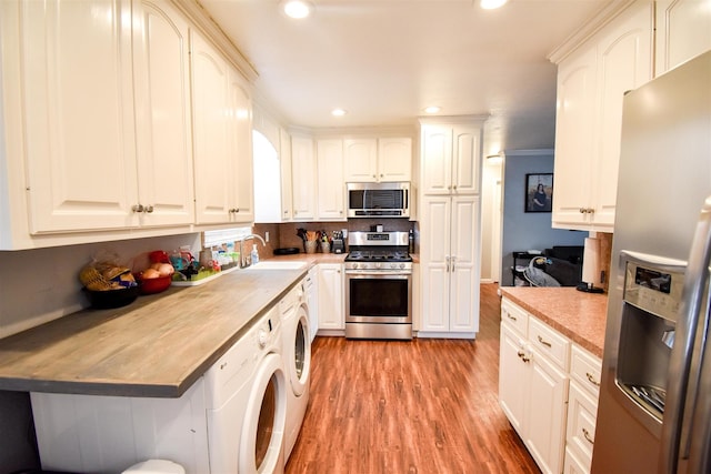 kitchen with sink, light wood-type flooring, stainless steel appliances, and washer / clothes dryer