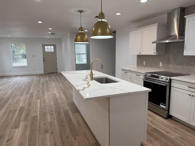 kitchen with white cabinetry, electric range, wall chimney exhaust hood, and an island with sink