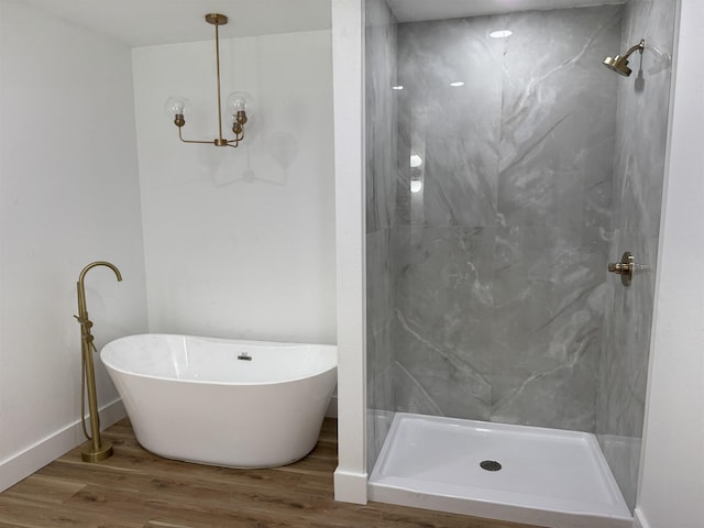 bathroom with hardwood / wood-style flooring, a notable chandelier, and independent shower and bath