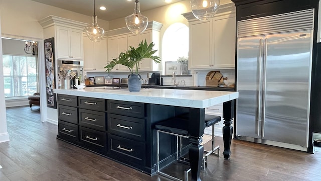 kitchen featuring stainless steel appliances, a kitchen island, white cabinets, and decorative light fixtures