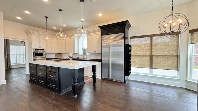 kitchen featuring an inviting chandelier, white cabinetry, stainless steel built in fridge, dark cabinets, and dark wood-style floors
