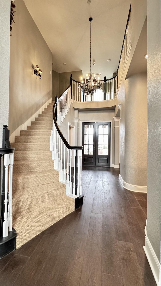foyer entrance with hardwood / wood-style floors, stairs, french doors, and an inviting chandelier