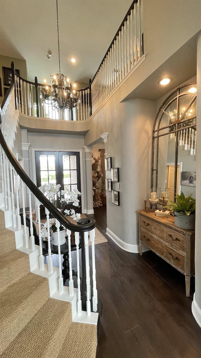 entrance foyer featuring a notable chandelier, a towering ceiling, dark wood-type flooring, and french doors