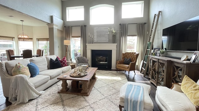 living room with a towering ceiling, plenty of natural light, a chandelier, and ornate columns