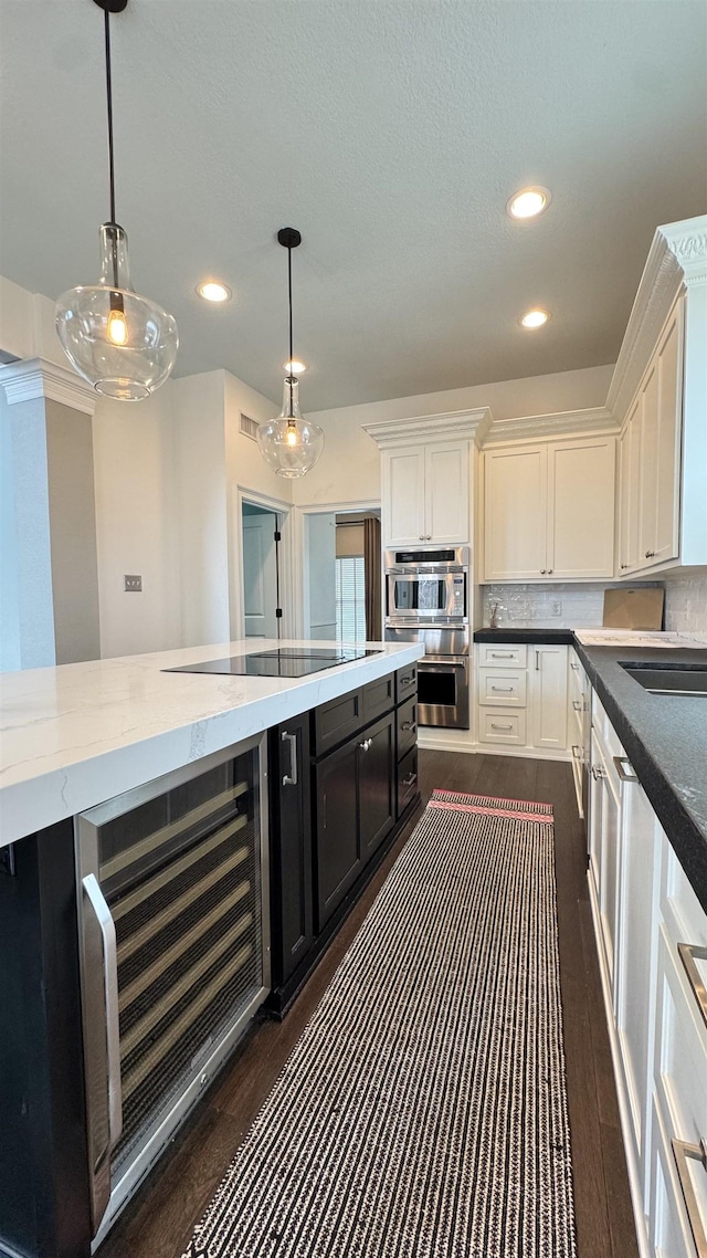 kitchen featuring double oven, white cabinets, black electric stovetop, and decorative light fixtures