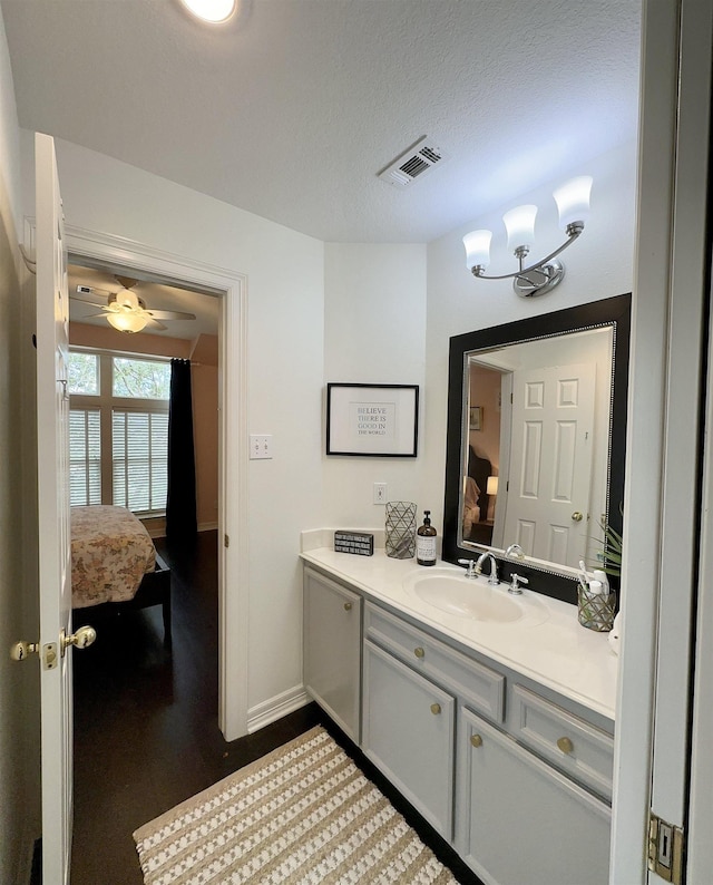 bathroom with ceiling fan, vanity, and a textured ceiling