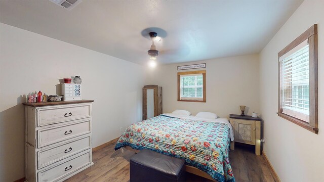 bedroom featuring multiple windows, ceiling fan, and hardwood / wood-style floors