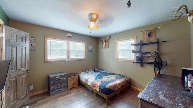 bedroom with hardwood / wood-style floors, a textured ceiling, and ceiling fan