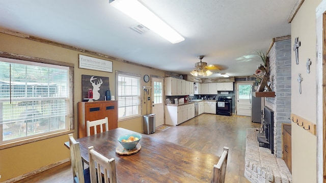 dining room with a fireplace, light wood-type flooring, and ceiling fan