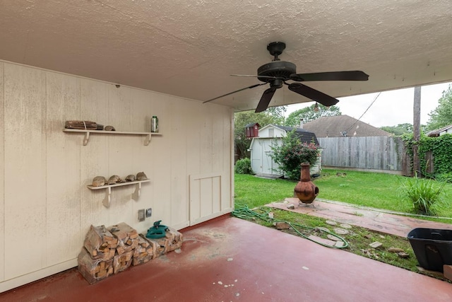 view of patio / terrace featuring an outbuilding, a ceiling fan, a storage unit, and fence