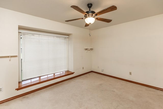 empty room with baseboards, ceiling fan, and light colored carpet