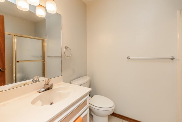 bathroom with vanity, toilet, and a shower with door