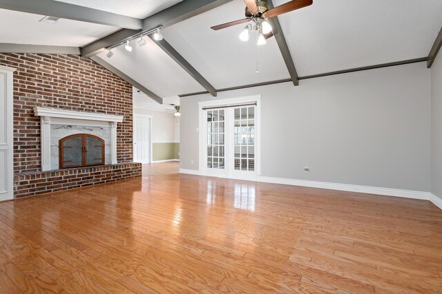 unfurnished living room featuring vaulted ceiling with beams, light hardwood / wood-style flooring, a brick fireplace, and ceiling fan