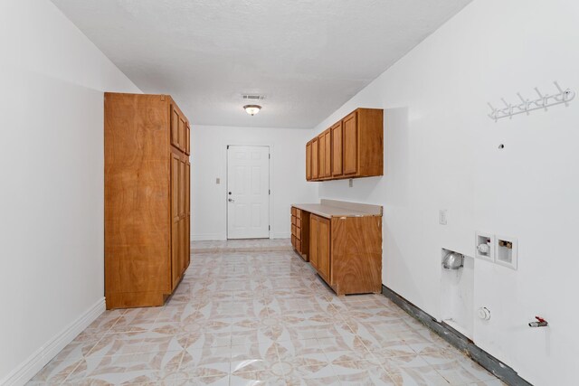 washroom featuring gas dryer hookup, cabinets, and a textured ceiling