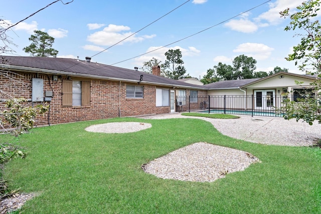 rear view of house with a yard, a patio, and a fenced in pool