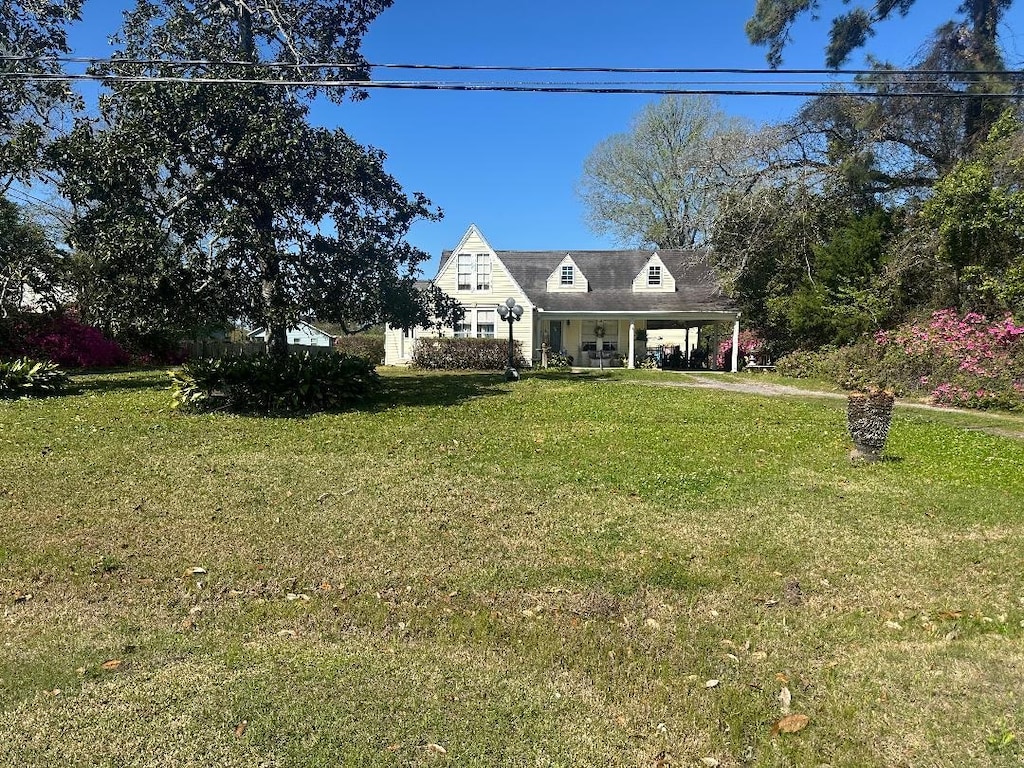 cape cod house featuring a carport and a front yard