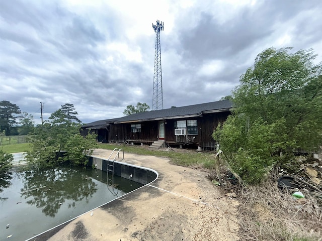 rear view of house featuring cooling unit, a patio, and an empty pool