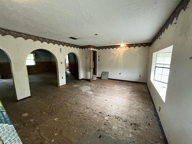 unfurnished living room featuring arched walkways and a textured ceiling