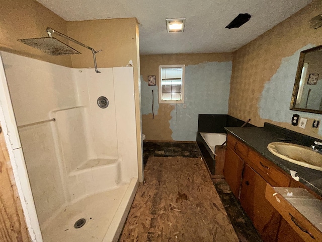 full bathroom featuring a shower stall, a bathing tub, vanity, and a textured ceiling