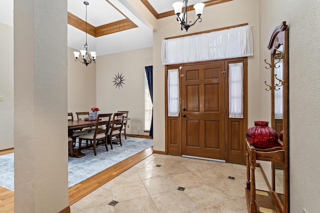 foyer entrance featuring light tile patterned floors, an inviting chandelier, and crown molding