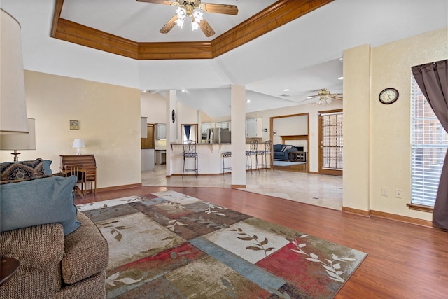 living room featuring hardwood / wood-style flooring, ceiling fan, crown molding, and a tray ceiling