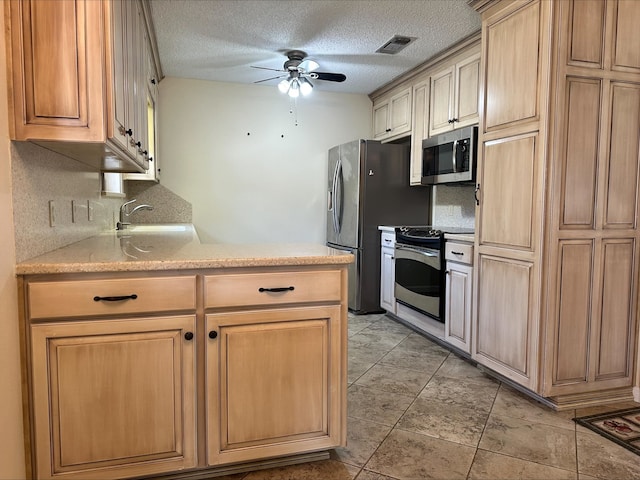 kitchen with sink, ceiling fan, appliances with stainless steel finishes, tasteful backsplash, and a textured ceiling