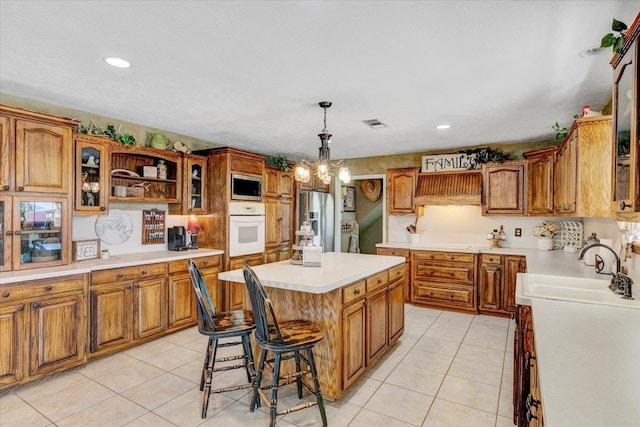 kitchen with a kitchen bar, appliances with stainless steel finishes, sink, pendant lighting, and a kitchen island