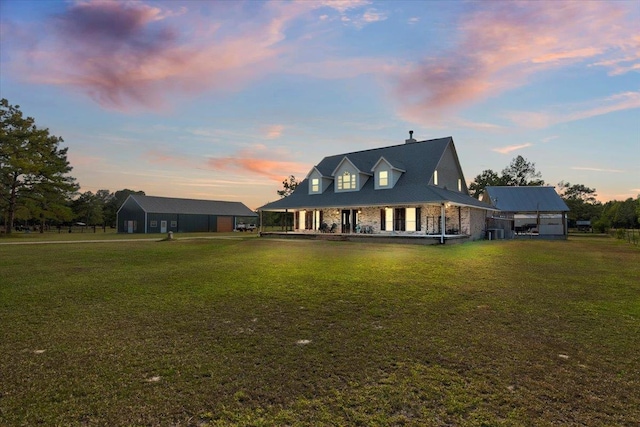 back house at dusk featuring a lawn