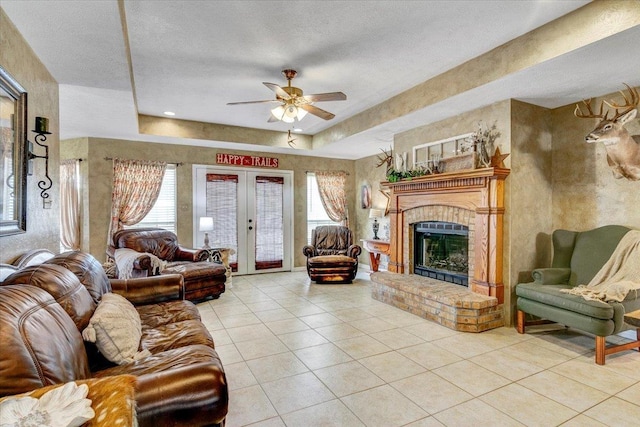 living room featuring a tray ceiling, french doors, a textured ceiling, and a brick fireplace