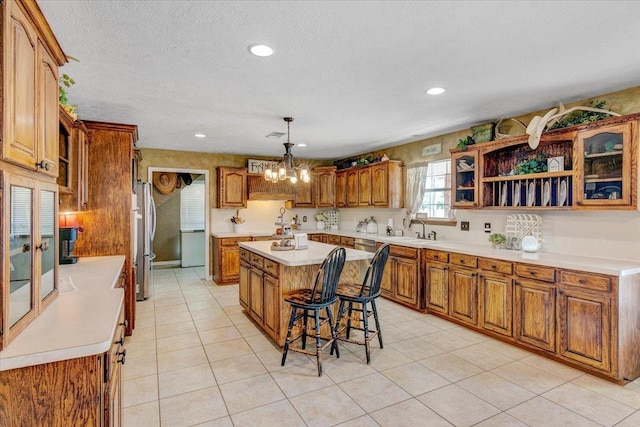 kitchen featuring an inviting chandelier, a kitchen breakfast bar, stainless steel fridge, decorative light fixtures, and a kitchen island