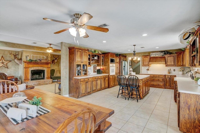 tiled dining area with ceiling fan with notable chandelier and sink