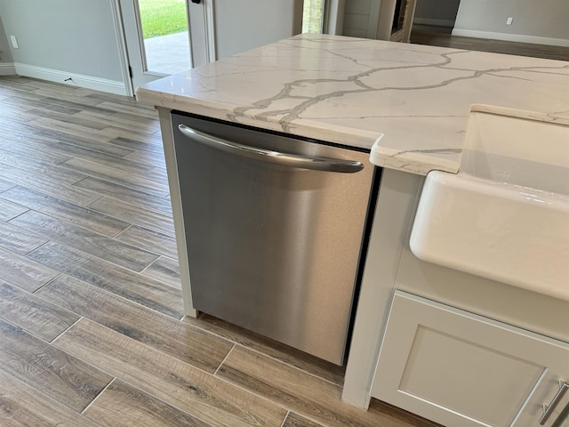 kitchen with light stone countertops, white cabinets, and stainless steel dishwasher