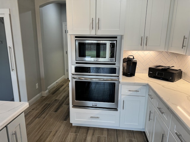 kitchen featuring white cabinets, appliances with stainless steel finishes, backsplash, and light stone countertops