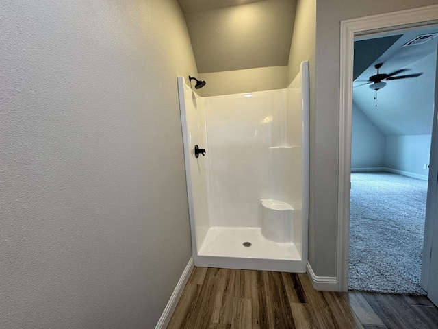 bathroom with ceiling fan, hardwood / wood-style floors, vaulted ceiling, and walk in shower