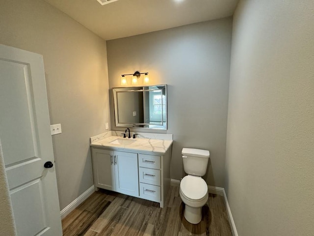 bathroom with wood-type flooring, vanity, and toilet