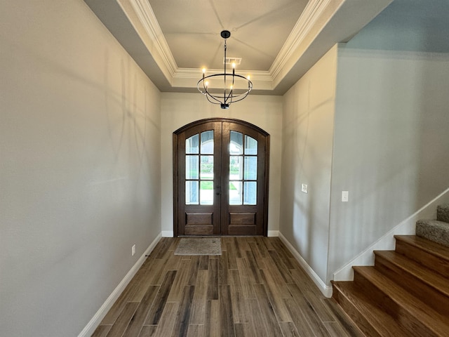 entryway featuring french doors, ornamental molding, a tray ceiling, dark hardwood / wood-style flooring, and a chandelier