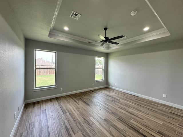 unfurnished room featuring a tray ceiling, crown molding, ceiling fan, and light wood-type flooring