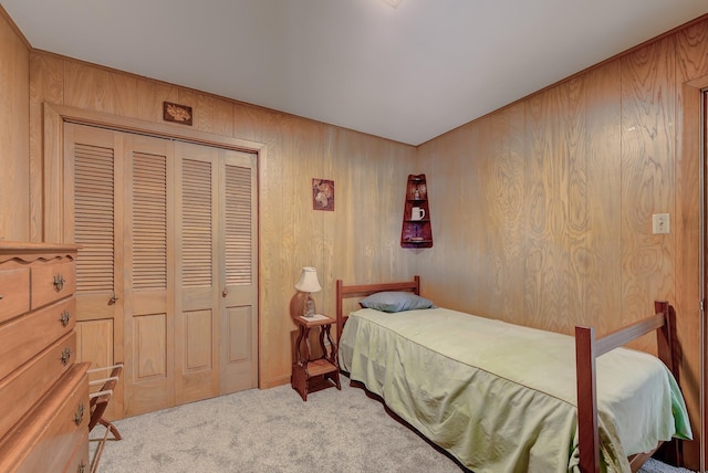 bedroom with light colored carpet, a closet, and wooden walls