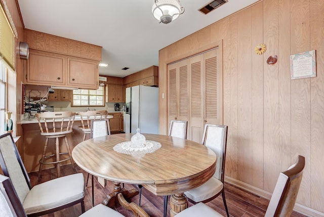 dining room featuring hardwood / wood-style floors and wooden walls