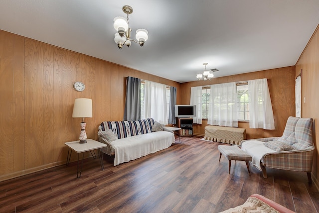 living room featuring wooden walls, dark hardwood / wood-style floors, and a notable chandelier