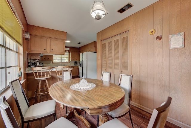 dining space with wood walls and hardwood / wood-style flooring