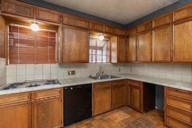 kitchen with dark parquet floors, black dishwasher, sink, gas stovetop, and a textured ceiling