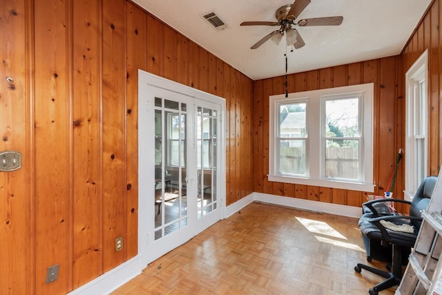 office with ceiling fan, light parquet floors, wooden walls, a textured ceiling, and french doors