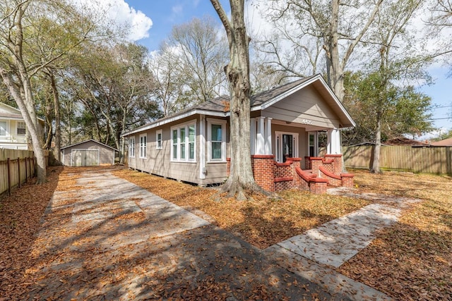 bungalow featuring a porch and a storage shed