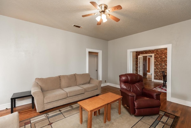 living room with ceiling fan, light hardwood / wood-style floors, and a textured ceiling